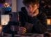 Männlicher Teenager sitzt in einem dunklen Zimmer mit Tarotkarten, Kristallen und Smartphone vor sich und beschäftigt sich mit spirituellen Social-Media-Inhalten.