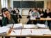 Erschöpfte Lehrerin sitzt nachdenklich am Pult, während Schülerinnen und Schüler sie im Unterricht besorgt ansehen. Symbolbild für Burnout an Schulen.